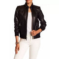 Person wearing a black leather jacket and white pants on a white background