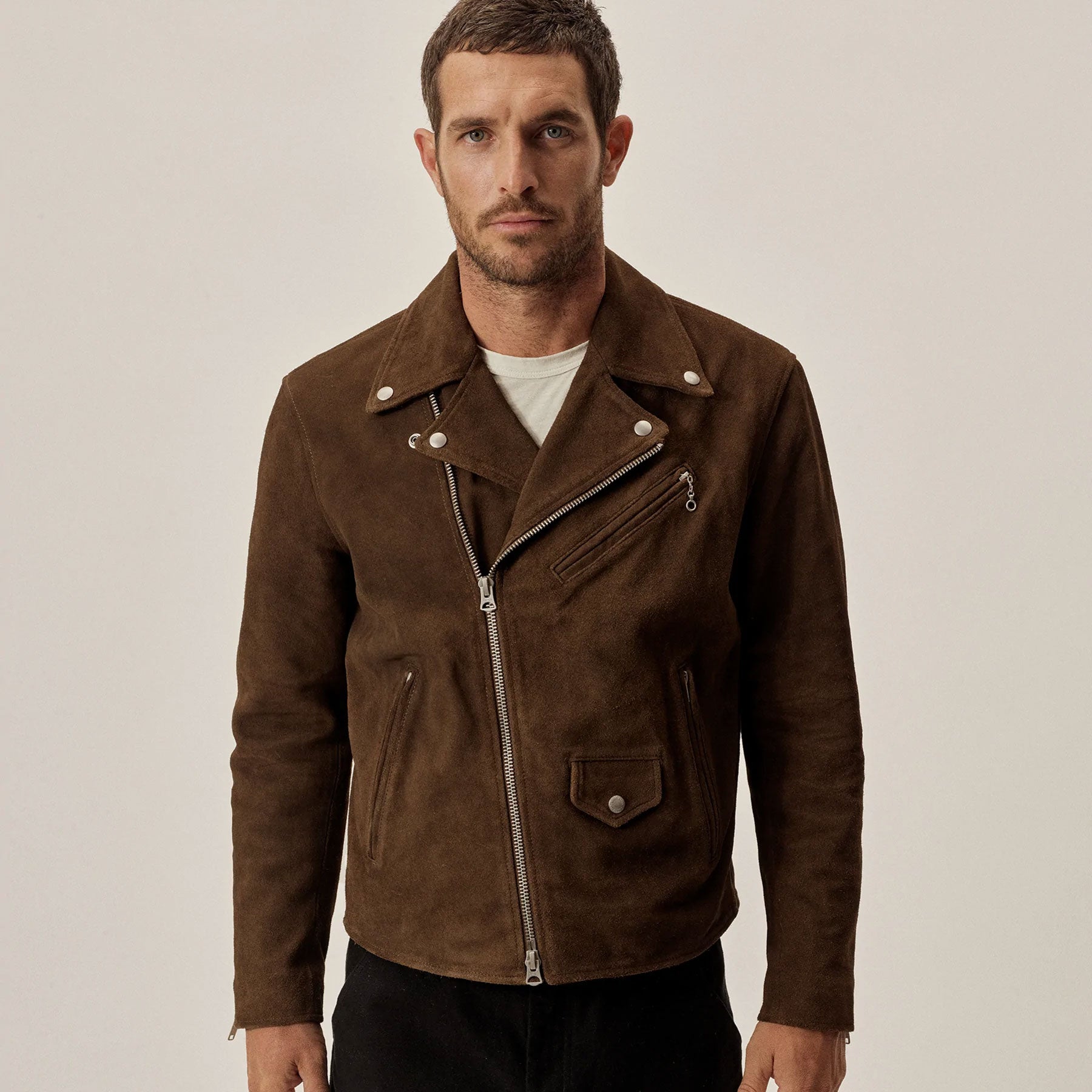Man wearing a brown suede jacket on a plain background