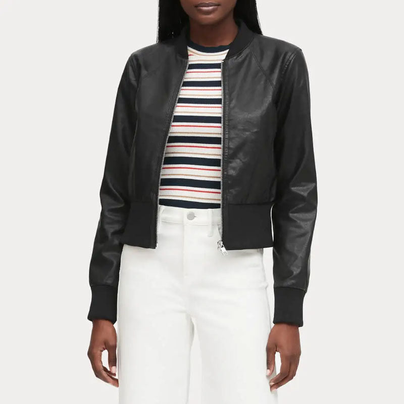 Person wearing a black leather jacket over a striped shirt with white pants on a light gray background