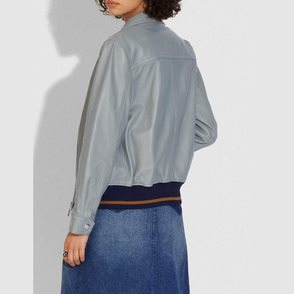 Person wearing a light gray jacket and blue jeans on a white background