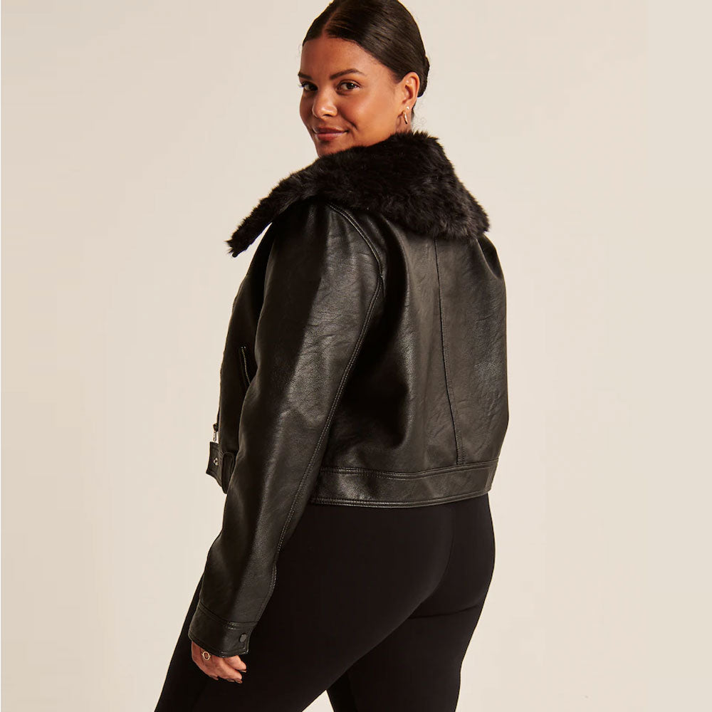 Woman wearing a black leather jacket with fur collar on a beige background