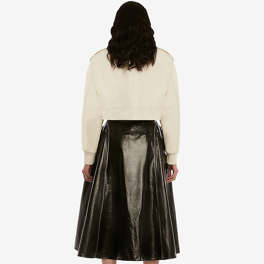 Person wearing a cream sweater and black leather skirt on a white background