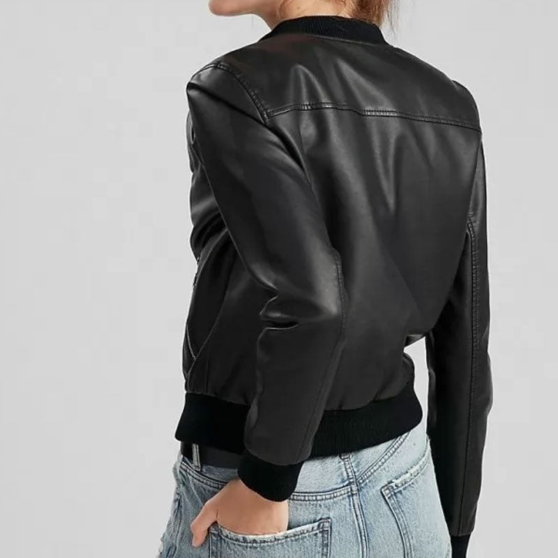 Person wearing a black leather jacket and light blue jeans on a plain background