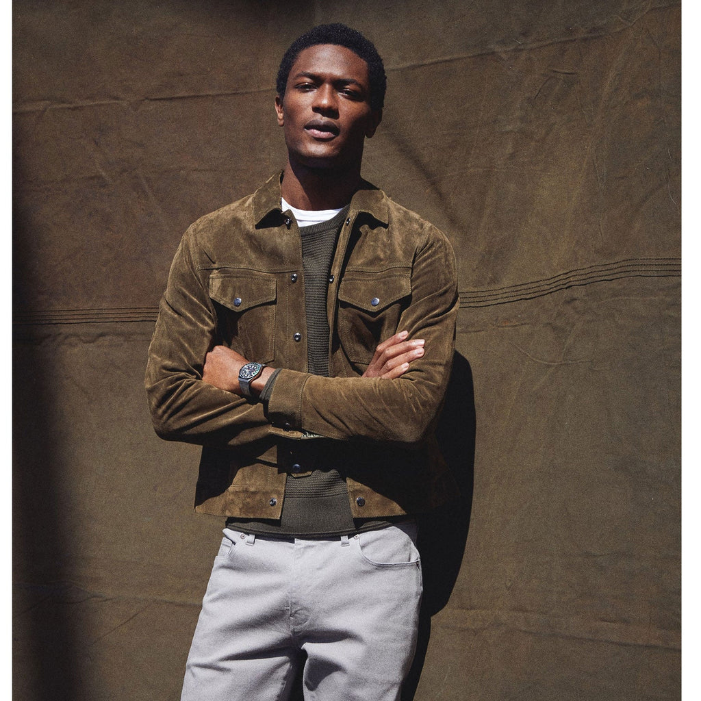 Man wearing a suede jacket against a textured brown background