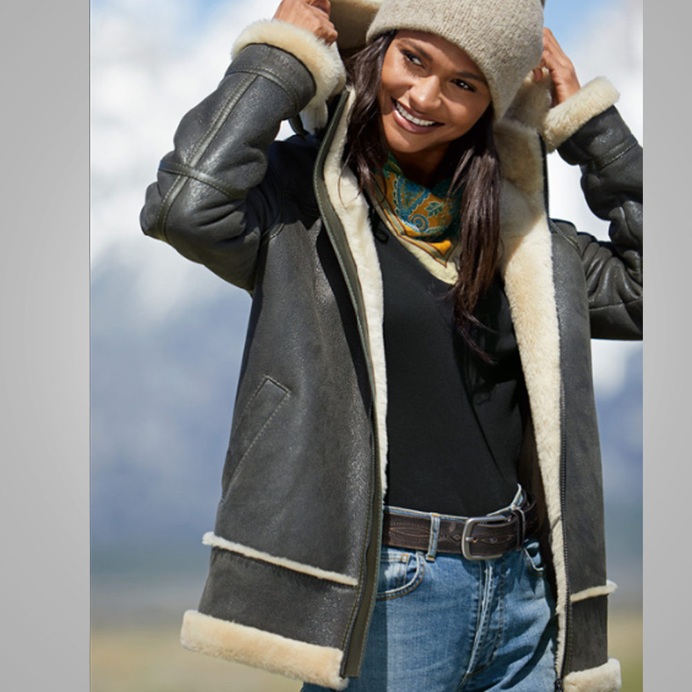 Woman wearing a gray shearling jacket with a blurred outdoor background