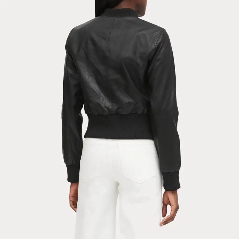 Person wearing a black bomber jacket and white pants on a white background