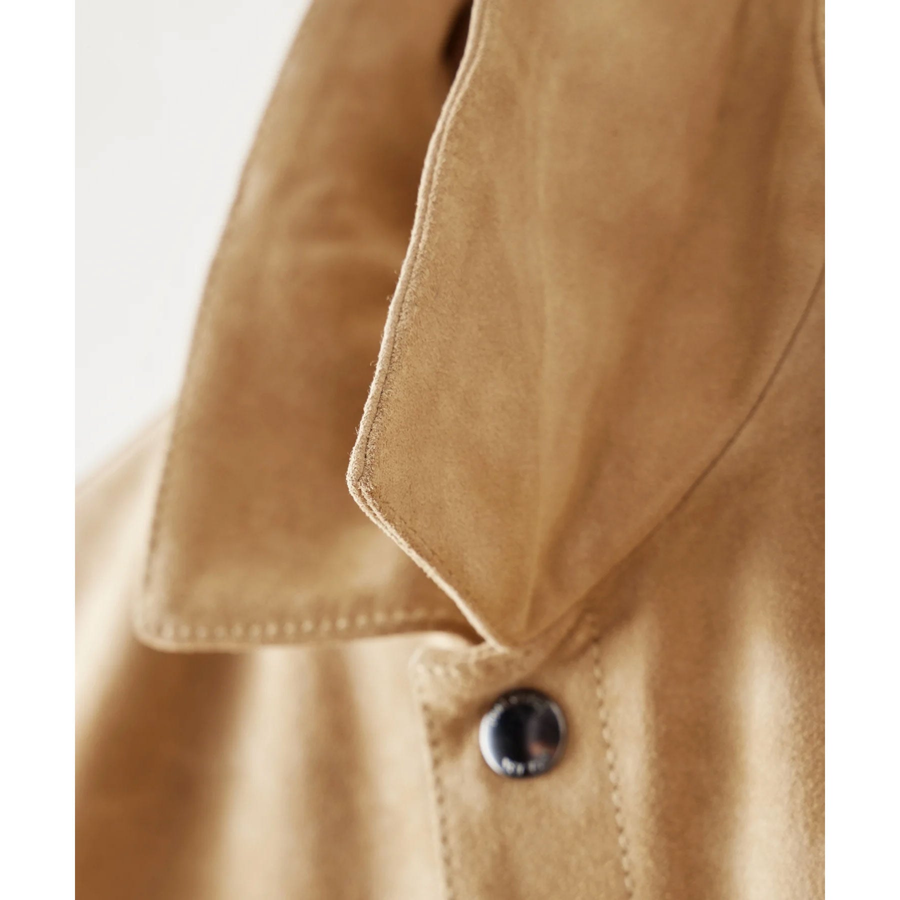 Close-up of a beige jacket with a button on a white background