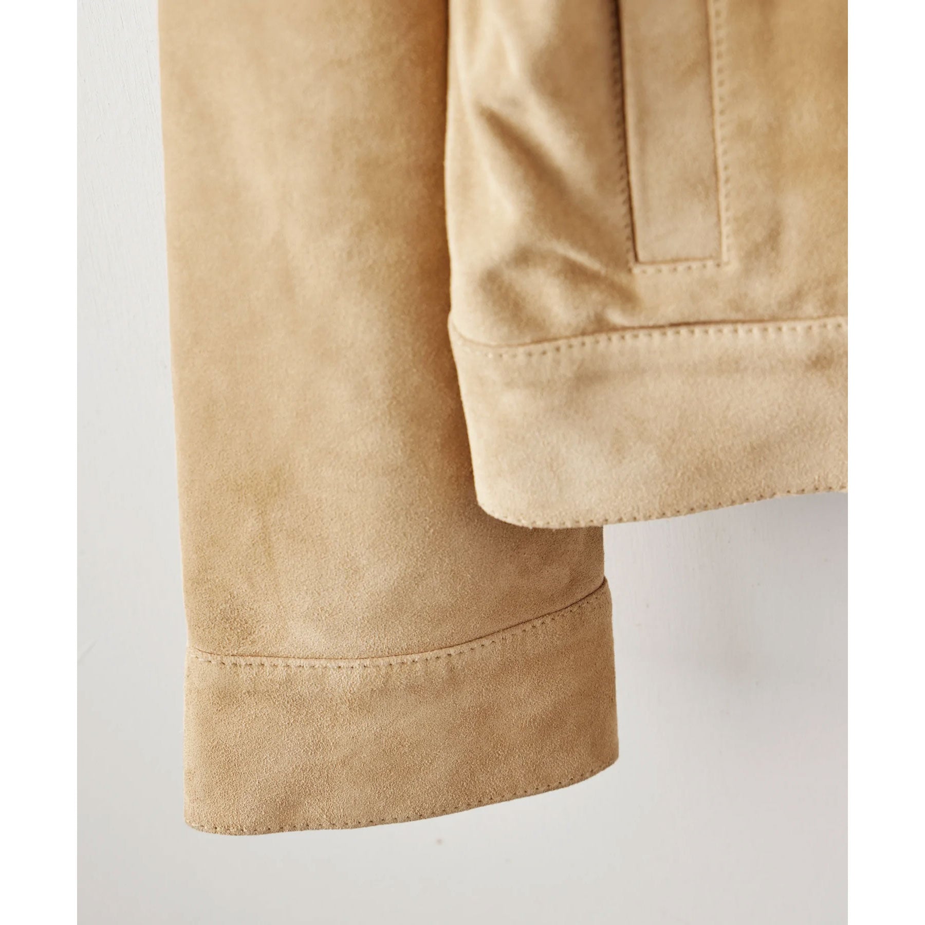 Close-up of beige fabric with a pocket on a light gray background