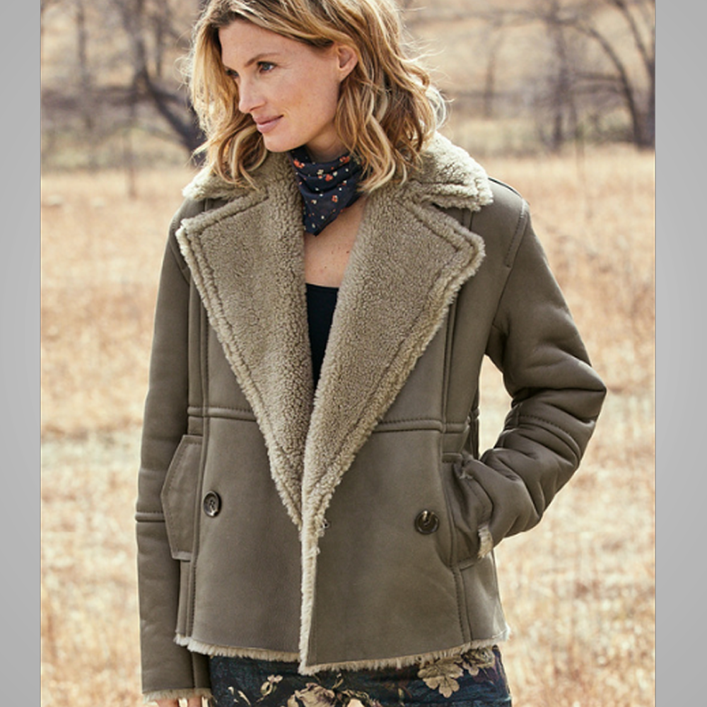 Woman wearing a brown coat with a fur-lined hood in a natural setting