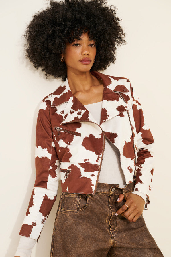 Person wearing a cow print jacket with a plain background