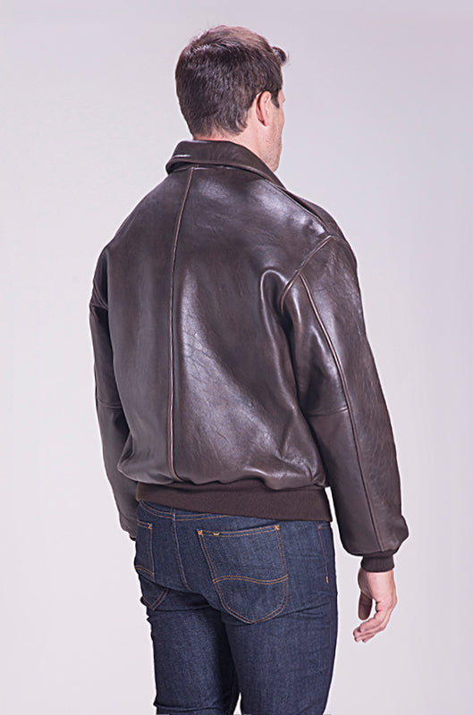 Man wearing a brown leather jacket and blue jeans on a white background