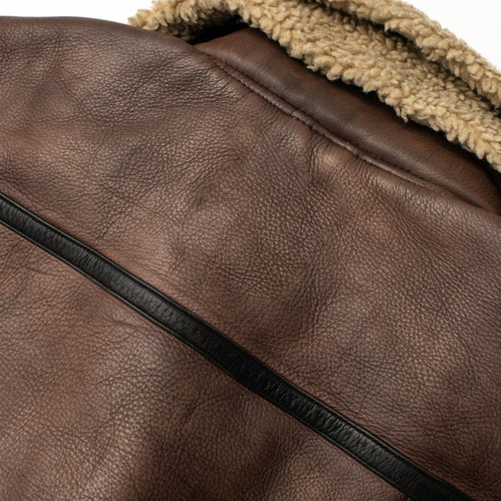 Close-up of a brown leather jacket with a zipper