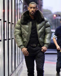 Man wearing a green puffer jacket with fox fur collar in an urban setting