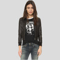 Woman wearing a black leather jacket, graphic t-shirt, and jeans on a light gray background