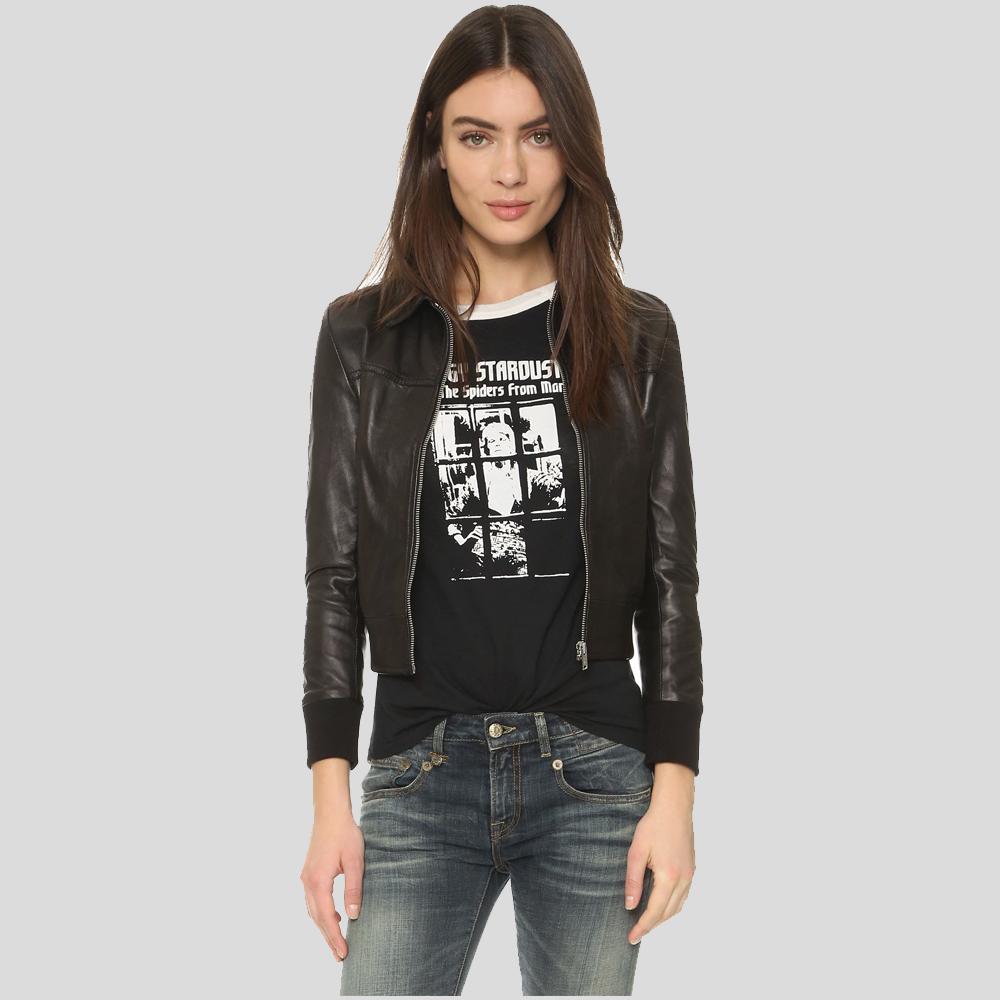 Woman wearing a black leather jacket, graphic t-shirt, and jeans on a light gray background