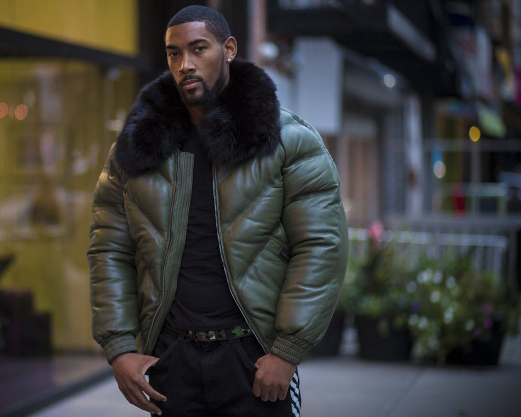 Man wearing a green puffer jacket with a fur-lined hood in an urban setting