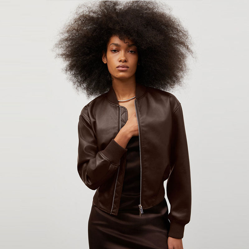 Woman wearing a brown leather jacket against a plain background