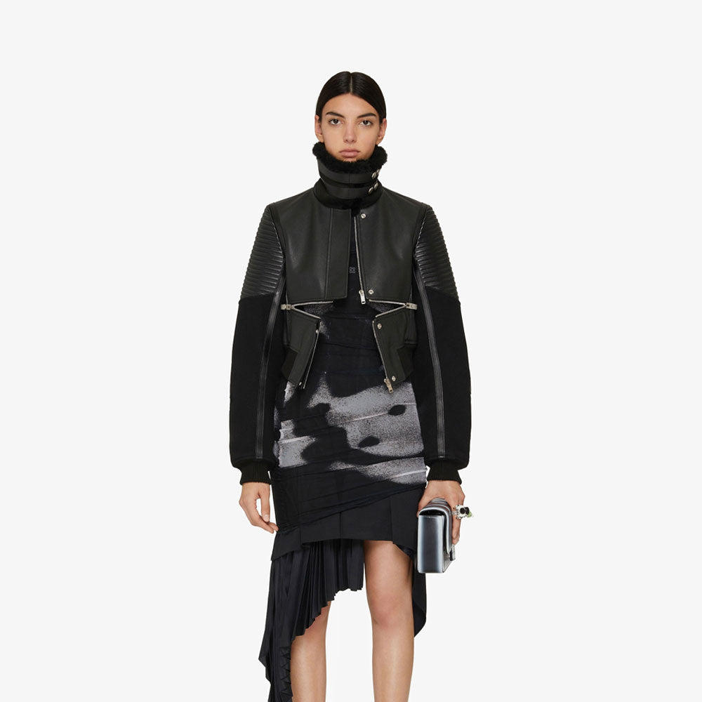 Person wearing a black leather jacket and dress with a white background