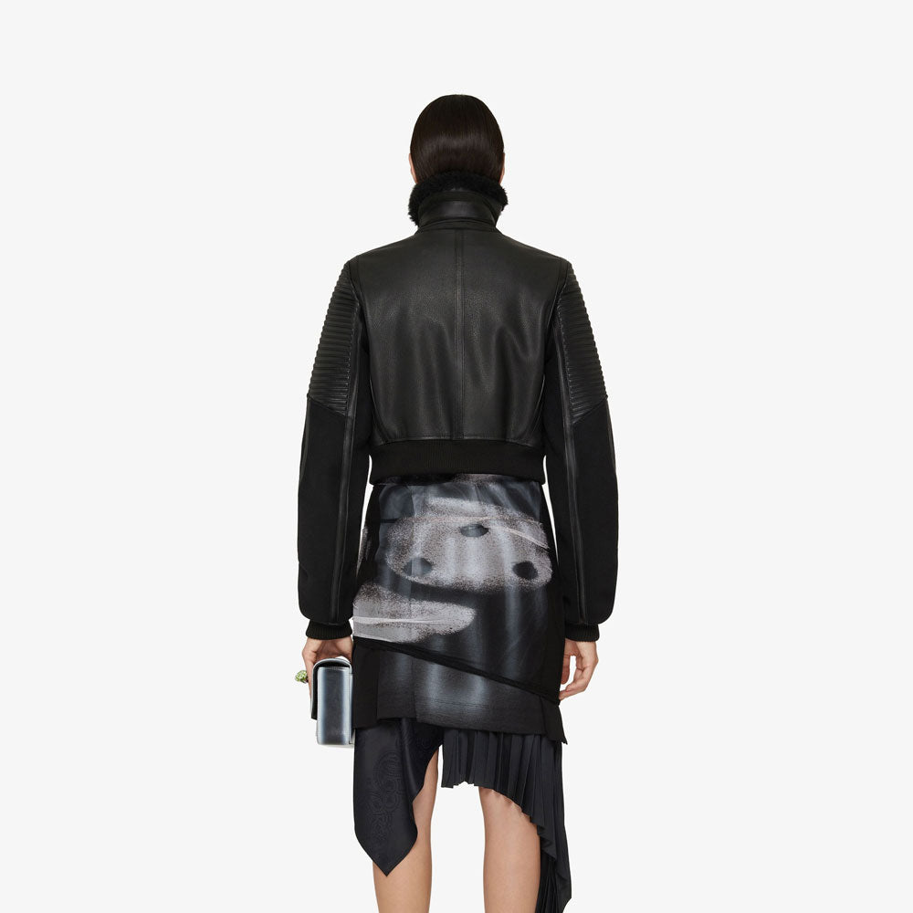 Person wearing a black leather jacket and skirt set on a white background