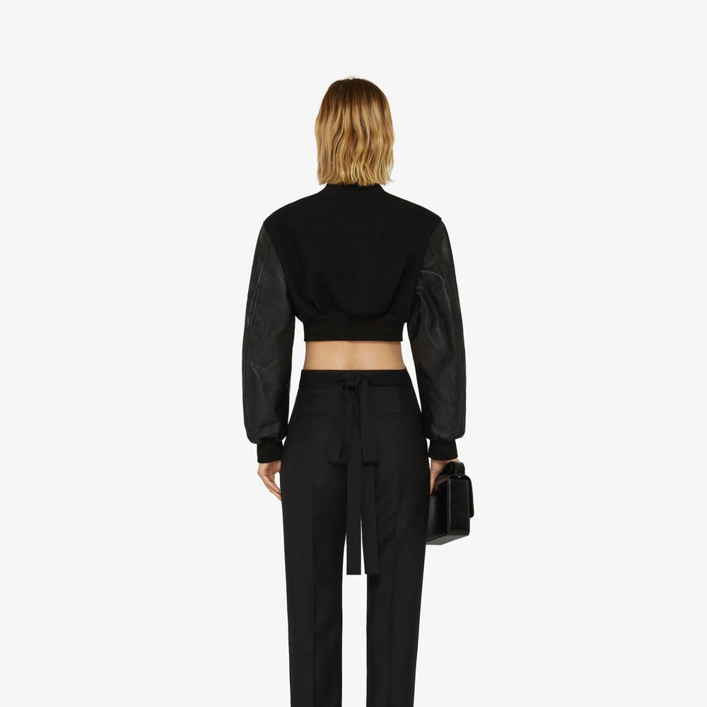 Person wearing a black outfit with a cropped top and high-waisted pants on a white background