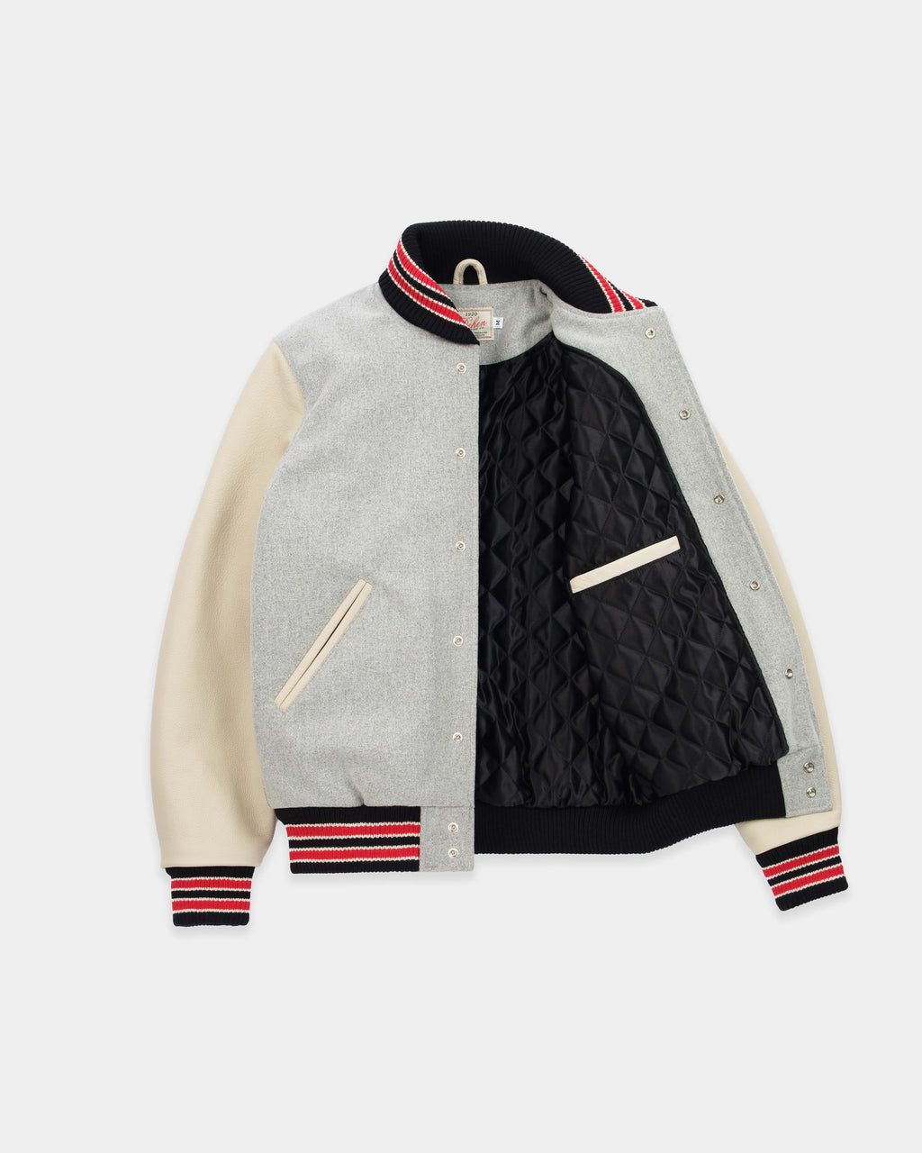 A varsity-style jacket with a light gray heather body, cream-colored sleeves, and a black quilted lining. It features red and navy striped ribbed trim on the collar, cuffs, and hem.