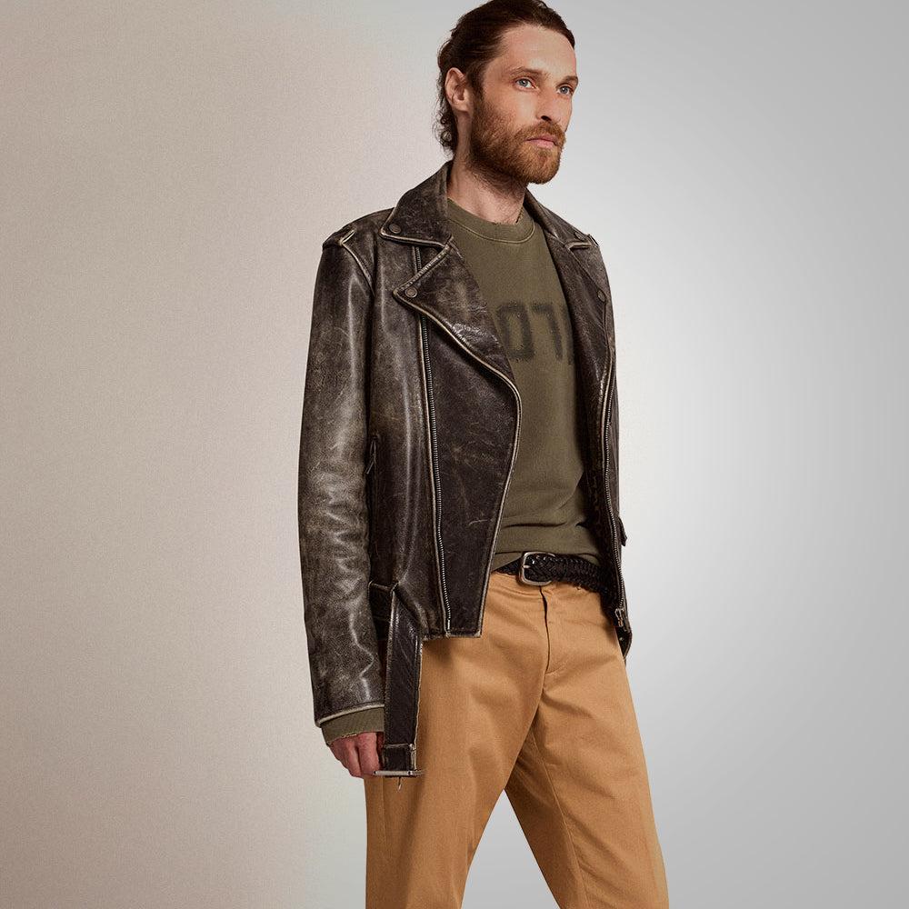Man wearing a brown leather jacket, green shirt, and tan pants on a plain background