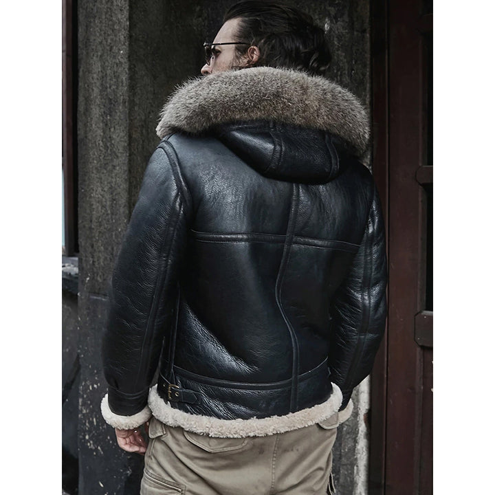 Person wearing a black leather jacket with fur trim standing against a dark background