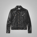 A black leather trucker jacket with a button-up front, two chest flap pockets, and two lower side pockets, displayed flat against a neutral gray background.