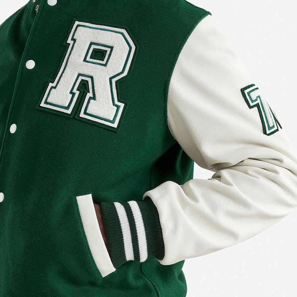 Close-up of a green and white varsity jacket with a large embroidered letter 'R' on the chest and a striped ribbed cuff.