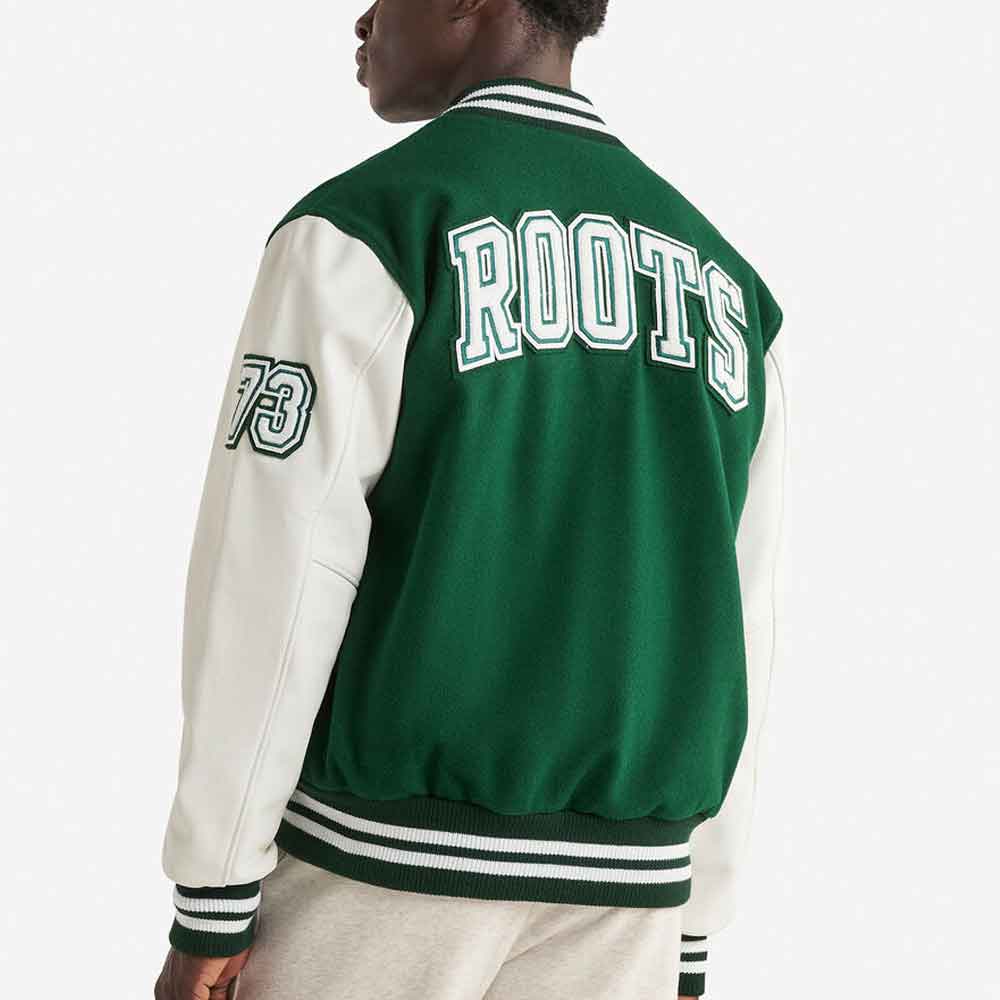 A person shown from the back wearing a green and off-white varsity jacket with 'ROOTS' and the number '73' on the back and sleeve.