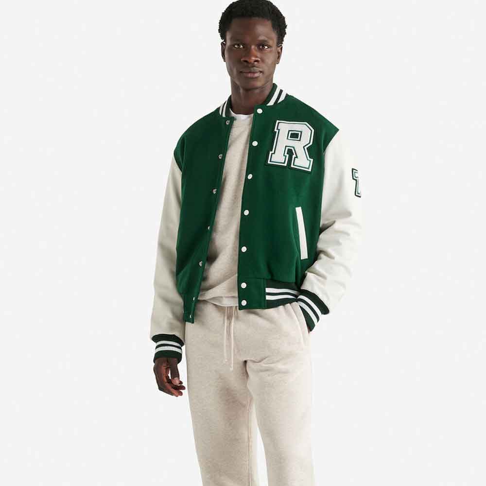 A man modeling a green and cream varsity jacket with a large white letter 'R' on the chest, paired with cream sweatpants and a cream t-shirt, against a light gray background.