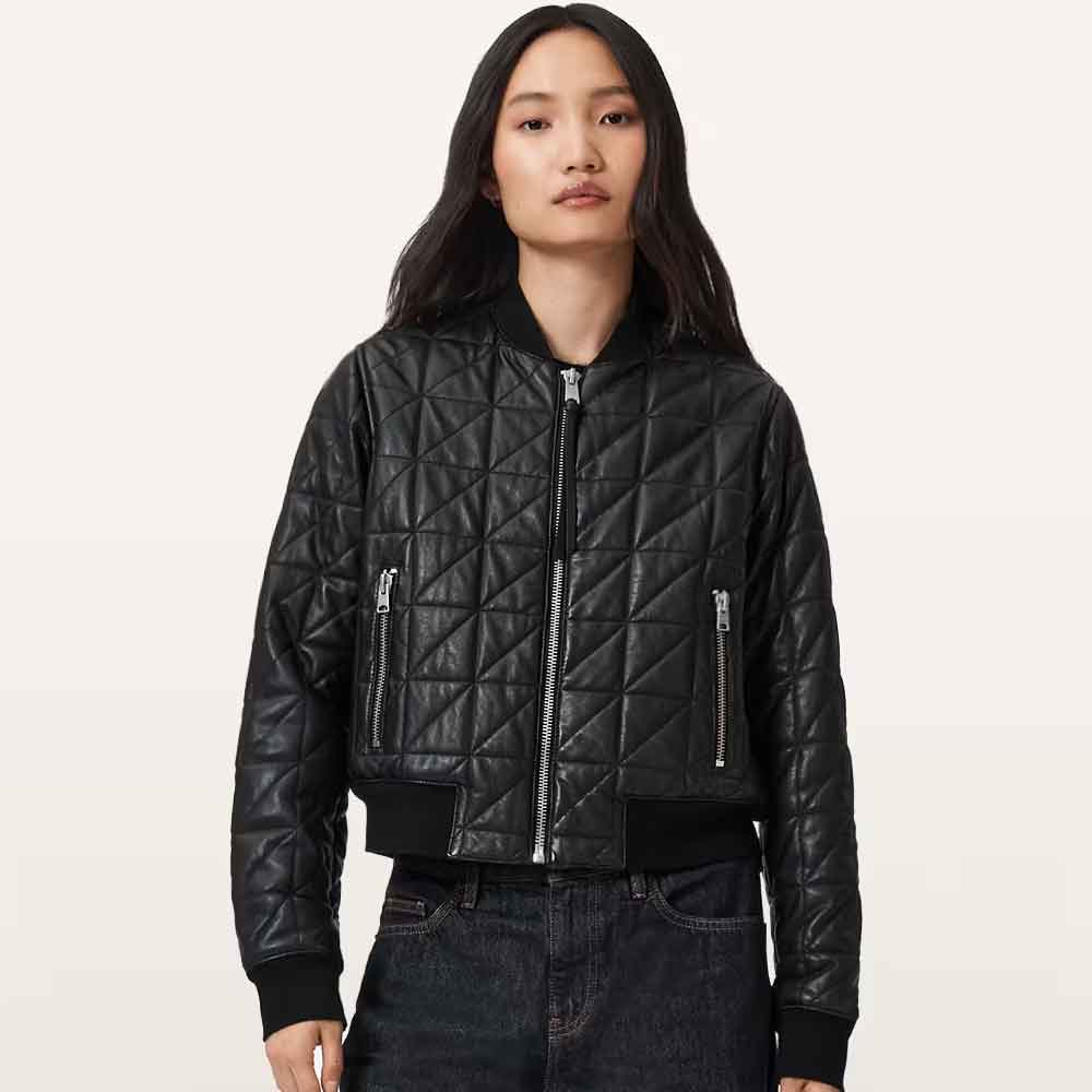 A model wearing a black quilted bomber jacket with silver zippers and a black ribbed collar, cuffs, and hem, paired with dark jeans against a light beige background.