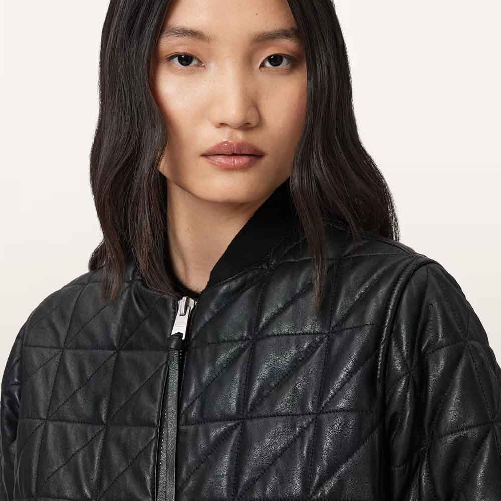 A close-up of a model wearing a black quilted faux-leather bomber jacket with a diamond-stitched pattern and a black collar, set against a plain light background.