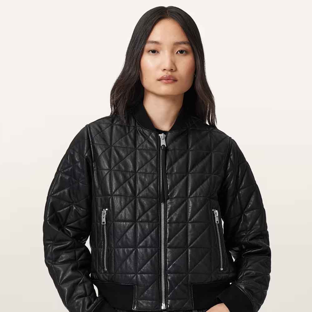 A model wearing a black quilted leather bomber jacket with silver zippers, photographed against a solid off-white background.