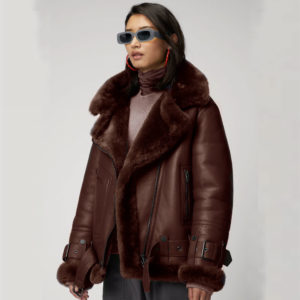 Person wearing a brown shearling jacket and sunglasses on a white background
