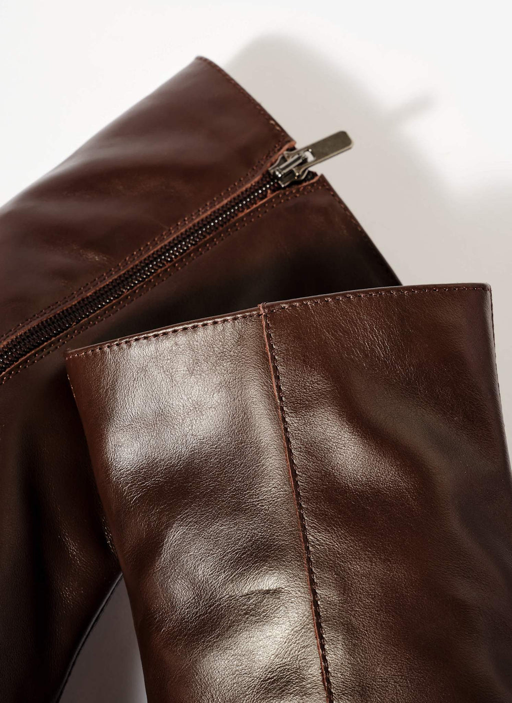Close-up of a brown leather jacket with a zipper on a white background