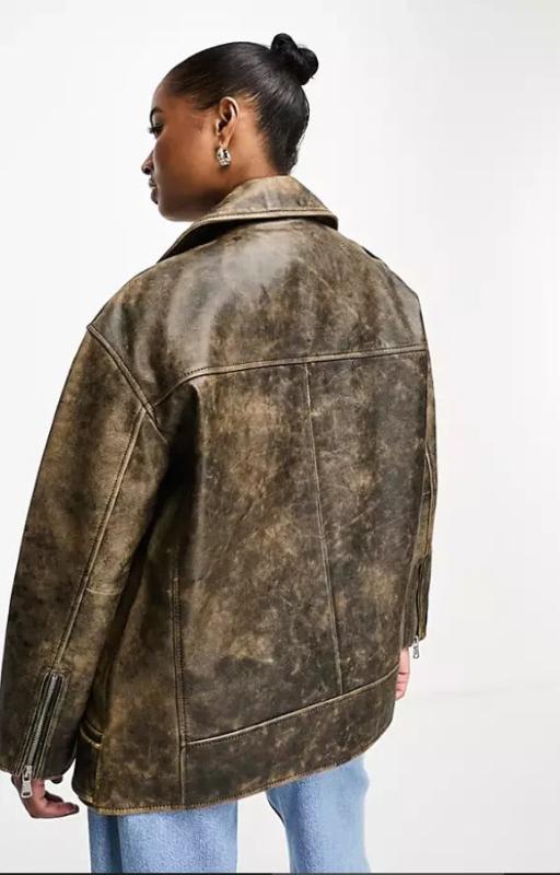 A person shown from the back wearing an oversized distressed leather jacket in a washed brown color, paired with light blue jeans, against a plain white studio background.