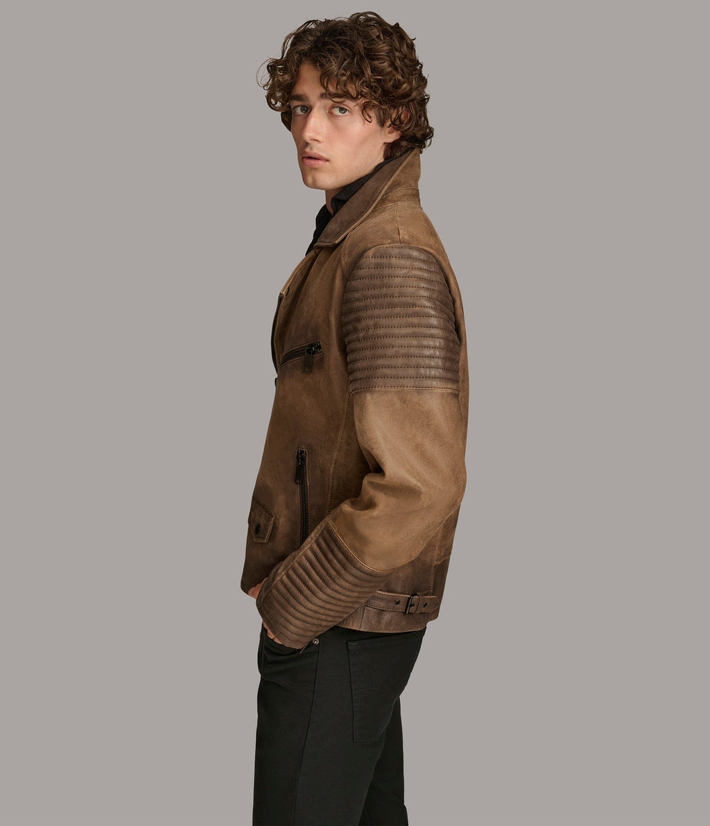 A man wearing a brown leather motorcycle jacket with textured horizontal paneling on the sleeves, shown in profile against a solid gray background.