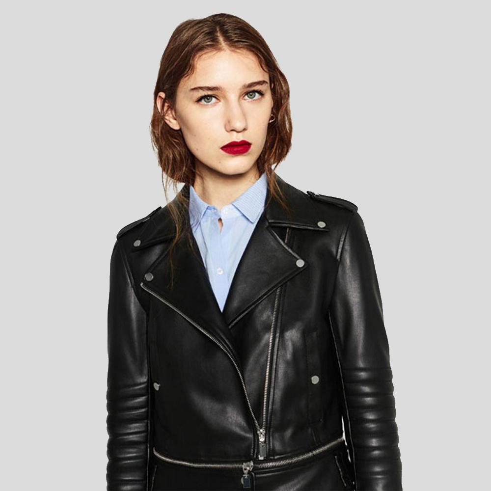 Woman wearing a black leather jacket over a light blue shirt on a gray background
