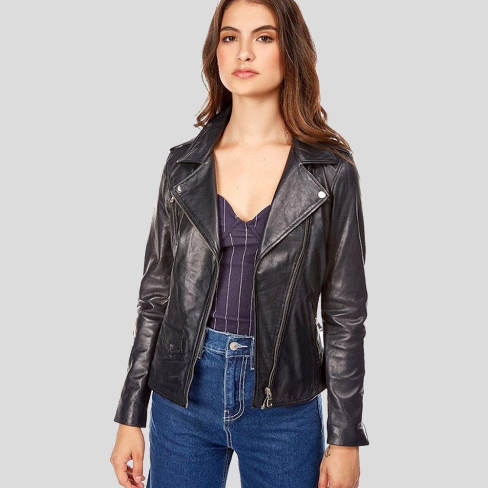 Woman wearing a black leather jacket, purple top, and blue jeans on a gray background