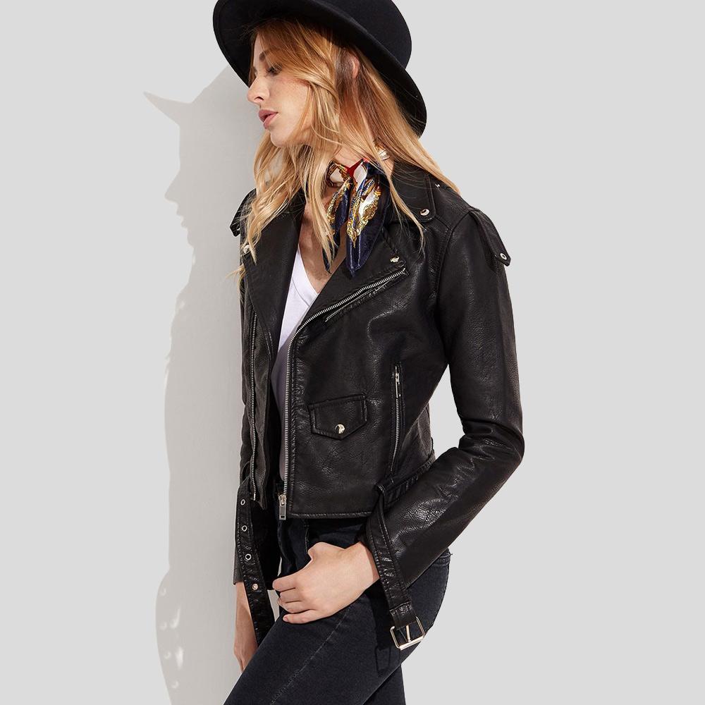 Woman wearing a black leather jacket and hat against a light background
