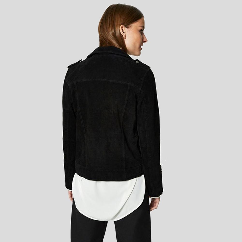 A woman shown from the back wearing a black suede or nubuck cropped jacket over a white top and black pants, photographed against a solid light gray studio background.