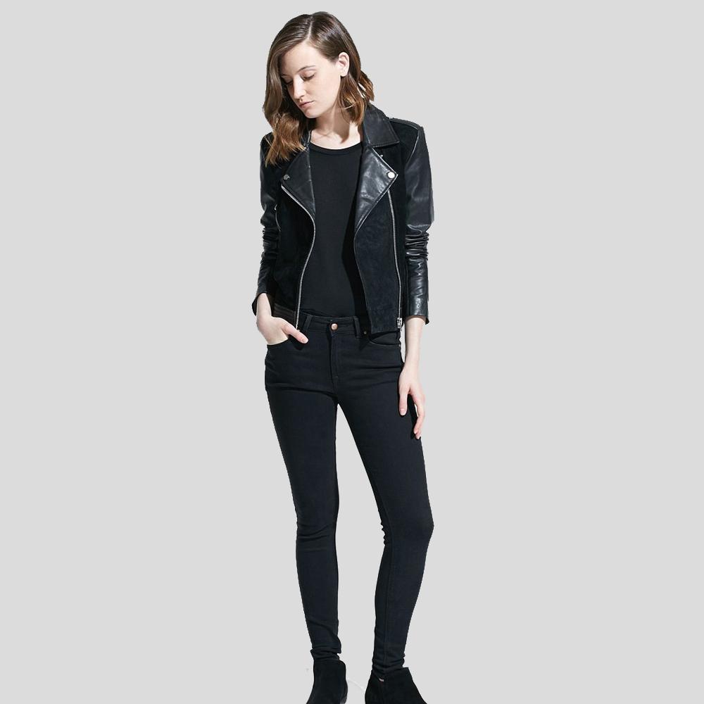 Woman wearing a black leather jacket and black jeans on a light gray background