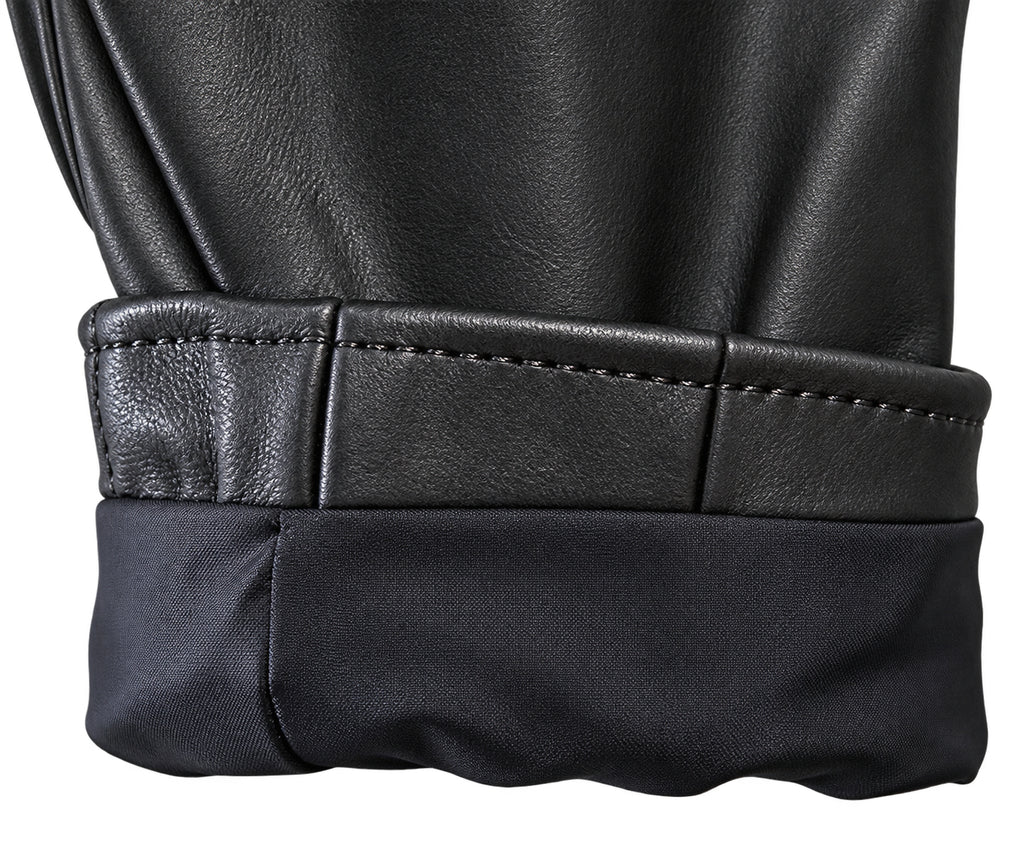 Close-up detail of a black leather jacket cuff with a rolled hem, showing the stitched leather edge and the dark fabric lining.
