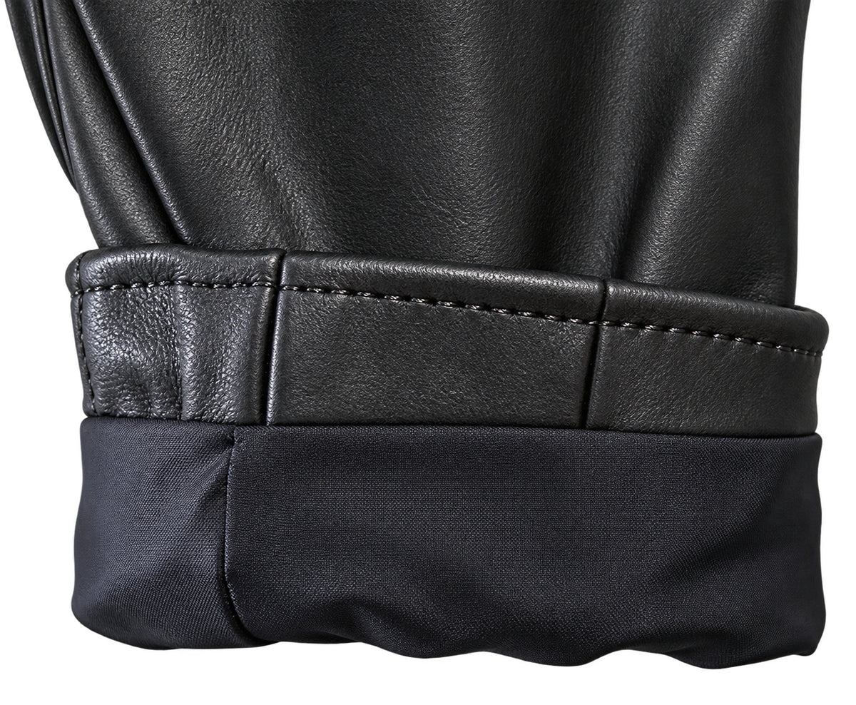 Close-up detail of a black leather jacket cuff with a rolled hem, showing the stitched leather edge and the dark fabric lining.