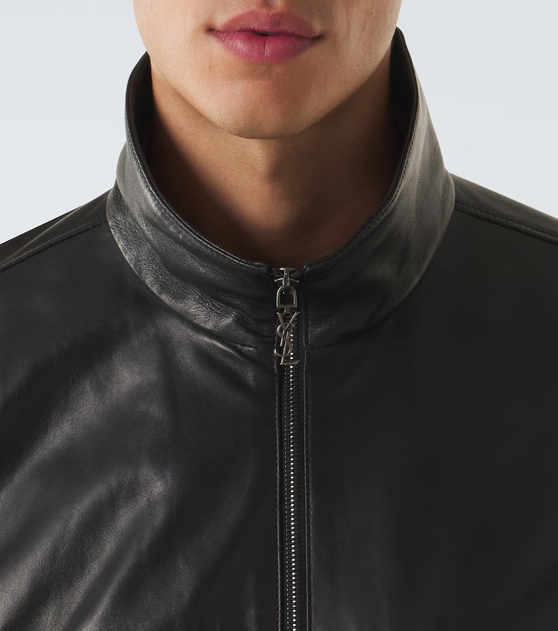 Close-up of a person wearing a black leather jacket with a high stand-up collar and a front zipper.