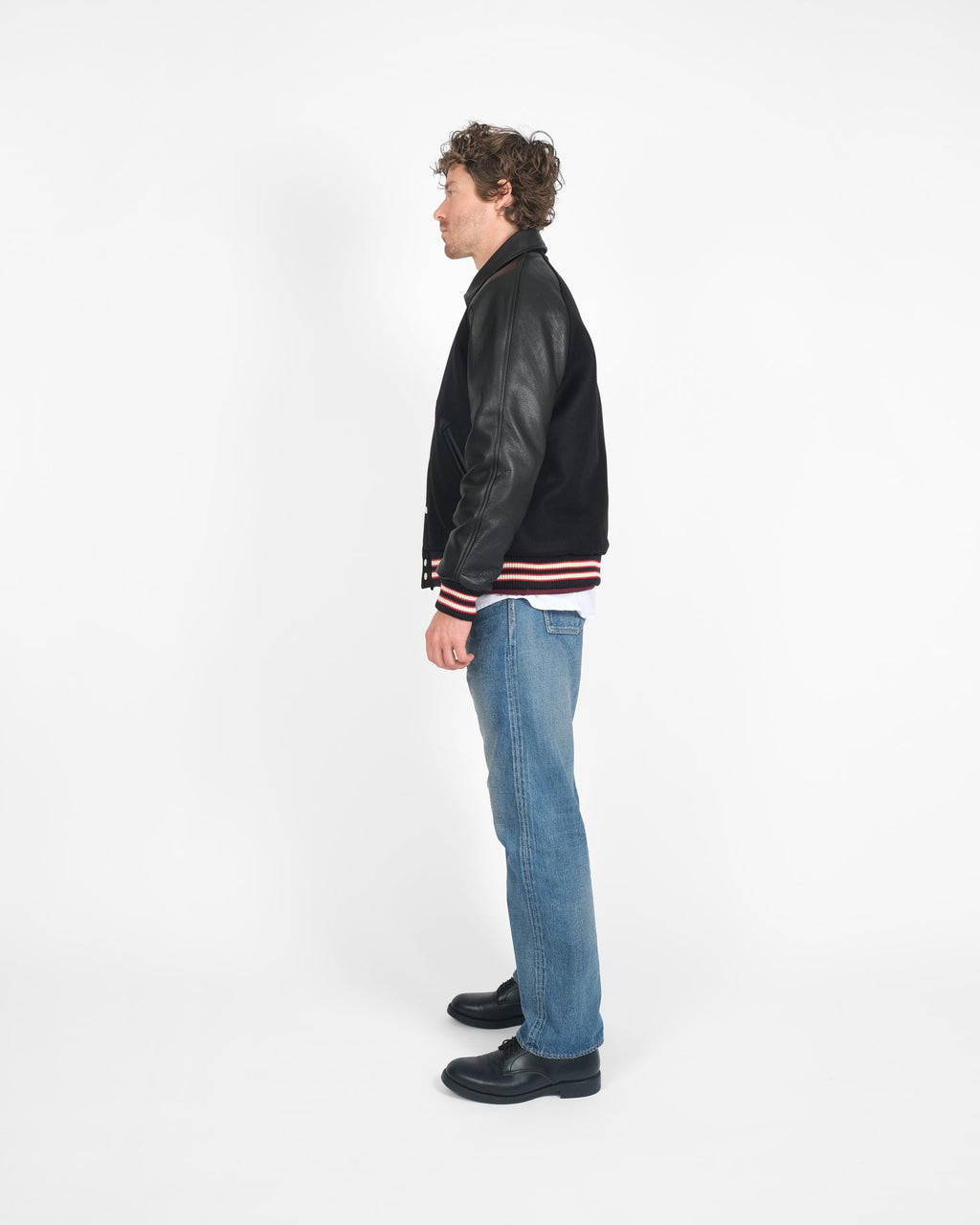 Person wearing a black varsity jacket with red and white stripes on a white background