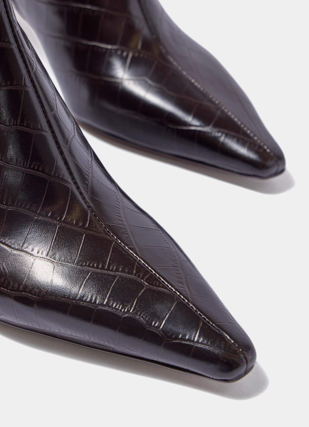 Close-up of black crocodile-patterned high-heeled shoes on a light background