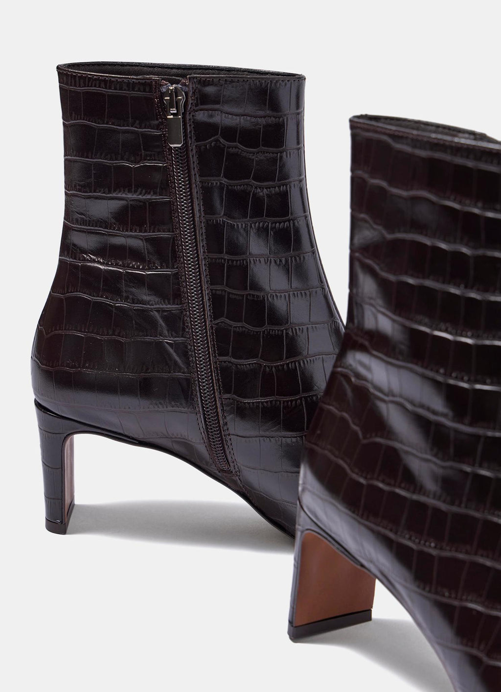 Pair of black crocodile-patterned boots on a white background