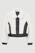 A cropped white fur jacket with black leather trim, a vertical front placket, a matching belt, and black ribbed side panels, shown on a light gray background.